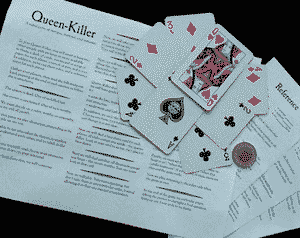 A sheet of paper with 'Queen-Killer' printed on it, some playing cards arranged in the shape of a star, and a coin