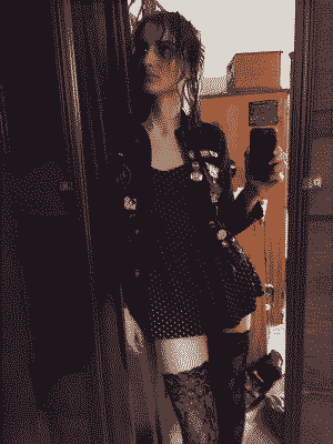 A full-body selfie of yours truly, wearing a denim jacket covered in pins and patches over a tiny polka-dot romper, and fishnet stockings.