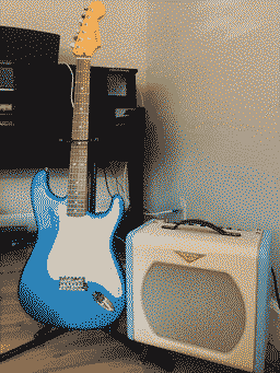 My electric guitar, on a stand next to my amp. The guitar is a sky-blue strat and the amp is this tiny little box that looks kind of like an old tv except in cute blue and white colors, sitting on four wooden legs.